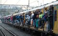 Bahnpendler halten sich an der Seite eines Personenzuges in Johannesburg.jpg